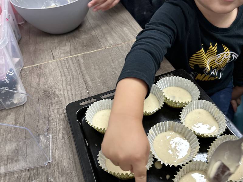 Dítě plní formičky těstem na muffiny